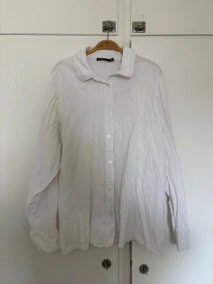 Vit oversized skjorta - Klassisk vit skjorta med avslappnad oversized passform och långa ärmar. Skjortan har knappar framtill och en mjuk krage, perfekt för en chill och stilren look. Skrynklig design, supersnygg! 