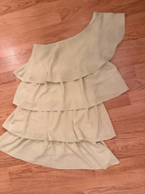 Ljusgul one shoulder volangklänning - Snygg ljusgul Zara klänning. Jättepopulär som tyvärr inte säljs längre. I fint skick men är typ lite limegul i färgen så man har koll på det. Liten i stl skulle säga att det är. Xs-S