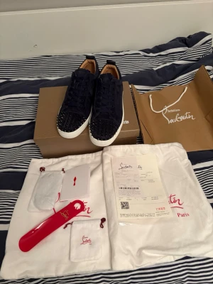 Mörkblå Christian Louboutin sneakers - Snygga mörkblå sneakers från Christian Louboutin i mocka med vita sulor och svarta nitar på tån. Skorna har klassisk låg profil och lyxig känsla med detaljer i läder. Perfekta för dig som vill sticka ut med exklusiv stil.                                  Har använt 2 gånger bara Dm vid pris förslag eller mer bilder och annat. 