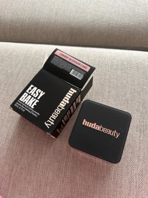 Huda Beauty Easy Bake Cherry Blossom - Loose baking & setting powder från Huda Beauty i nyansen Cherry Blossom Cake. Kommer i en fyrkantig svart burk med rosa detaljer och matchande kartong. Perfekt för att fixera foundation och ge en matt finish. Innehåller 20g. Oanvänt 