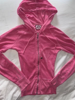 Rosa velourhoodie från Juicy Couture - Säljer en rosa hoodie från Juicy Couture i velour. Hoodien har dragkedja, huva med dragsko och ribbade muddar. Perfekt för dig som gillar Y2K-stil och vill ha något riktigt comfy och snyggt. 🎀✨