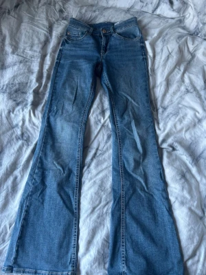 Blå bootcut jeans från Vero Moda - Säljer ett par snygga blå bootcut jeans från Vero Moda. Jeansen har klassisk femficksmodell, medelhög midja och utsvängda ben.