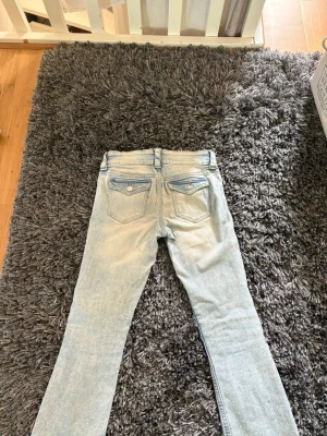 Ljusblå raka jeans med fickor - Säljer ett par ljusblå jeans med raka ben och klassisk femficksdesign. Jeansen har bälteshällor och knappgylf. Materialet är denim i bomull och passformen är avslappnad. Perfekta för en casual look.