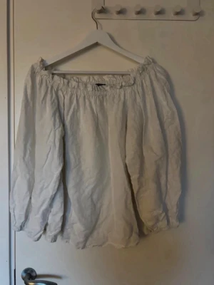 Vit offshoulder blus i linne -  En luftig vit offshoulder-blus med långärmad design och resår vid axlarna. Perfekt att styla med jeans eller kjol!💞