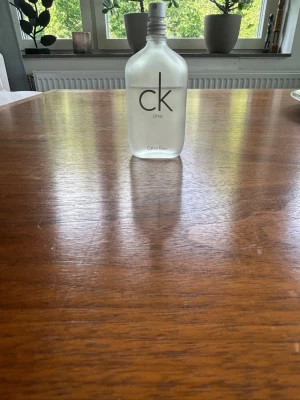 CK One parfym från Calvin Klein - Säljer en klassisk CK One parfym från Calvin Klein. Flaskan är i frostat glas med minimalistisk design och silverfärgad spraykork. Doften är unisex och fräsch, perfekt för dig som gillar stilrena och tidlösa parfymer. Perfekt till sommar, vår, eller all around. Ungefär 30-35 ml kvar i flaskan.