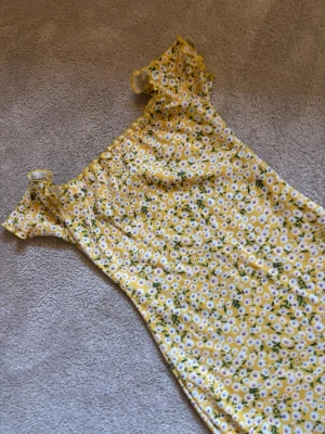 Gul blommig offshoulder klänning från shein i storlek xs - Söt gul klänning med vita och gröna blommor i ett figurnära snitt. Offshoulder-modell med korta volangärmar och stretchigt material som ger en bekväm passform. Perfekt för sommarens alla tillfällen!