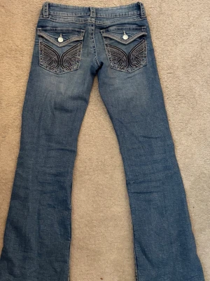 Bootcut lågmidjade jeans strl 152 från Gina Tricot. - Säljer ett par lågmidjade bootcut jeans från Gina Tricot i storlek 152. Jeansen är i ett bra skick men de har använts många gånger men har inga hål eller fläckar. Dem har vingar på fickorna och är klassiska trendiga jeans inom stockholmsstilen.