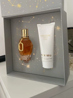 Million Gold parfymset för henne - Lyxigt parfymset från RebAnne med Million Gold for Her. Innehåller en elegant, guldtonad parfymflaska med geometrisk design och guldfärgat lock samt en vit body lotion med gulddetaljer. Perfekt presentförpackning med stjärnmönster.