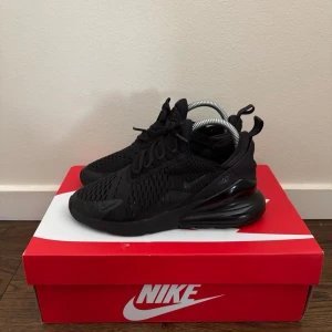 Nike Air Max 270 helsvarta sneakers - Nike Air Max 270 sneakers i helsvart med mesh-ovandel och stora synliga Air-enheter i hälen. Snygg sportig siluett med diskreta detaljer och klassisk Nike-logga på sidan. Skorna har snörning och en chunky sula för extra komfort. Finns 4 hål men kan ba visa 2, för de andra 2 skriv privat 