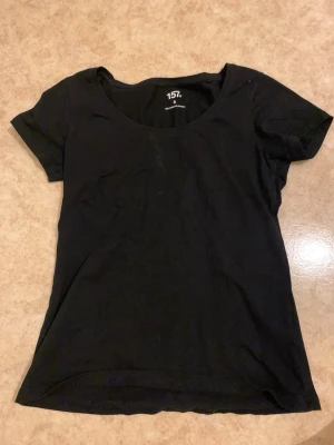 Svart basic t-shirt från 157 - En enkel svart t-shirt från 157 med rund halsringning och korta ärmar. Tillverkad i mjuk bomull som känns skön mot huden. Perfekt att matcha med jeans eller shorts för en clean och stilren look.