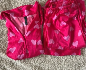 Viral slutsåld pyjamas från Hunkemöller - Söt tvådelad pyjamas i starkt rosa med ljusrosa hjärtan över hela tyget. Skjortan har krage, knappar framtill och långa ärmar. Byxorna har resår i midjan för extra komfort. Perfekt för mysiga kvällar hemma.