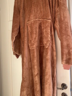 Brun fluffig loungewear hoodie - Mysig oversized loungewear hoodie i mjukt, brunt fleece-material. Har stor magficka framtill och långa ärmar med ribbade muddar. Perfekt för att chilla hemma och hålla sig varm under kalla dagar.