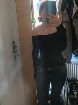 Svart offshoulder topp - Säljer en svart offshoulder topp med lång ärm. Toppen har en tight passform och sitter snyggt över axlarna. Perfekt att styla med jeans eller kjol för en trendig look.