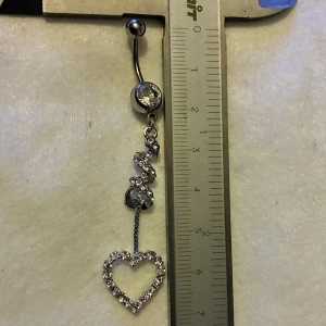 ✨ NY oanvänd navelpiercing med hänge - Kirurgiskt stål 316L  - ✨ NYTT oanvänt smycke i kirurgiskt stål! 🌸 Hållbart & Rostfritt: Slitstarkt 316L-stål som inte oxiderar eller rostar av fukt. 🌸 Säkert: Industristandard, skonsamt för läkta piercingar.  🛍️ 30 % BUNDLE-RABATT! Köp fler artiklar från min shop och få 30 % på allt! ✨ 📦 Frakt: Endast spårbart via Plick SafePay för vår trygghet.