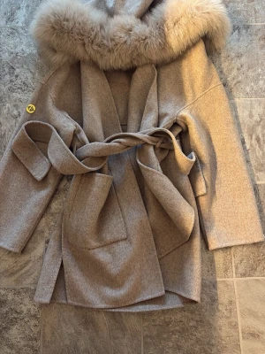 Beige kappa med fuskpäls och knytskärp - Ny kappa storlek xs-s säljer för 879 ⚠️inte jag på bilden eller jackan. Det är en exakt likadan som en annan tjej bär fast i en annan storlek⚠️