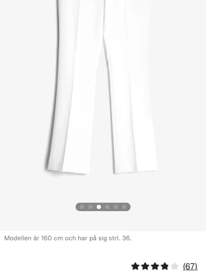 Vita utsvängda kostymbyxor - Snygga vita kostymbyxor med lågmidjad passform och utsvängda ben. Byxorna har stilrena pressveck och slitsar längst ner som ger en elegant och modern look.  Perfekta för både vardag och fest – matcha med en topp eller kavaj för en stilren outfit.  Storlek 38 och i mycket bra skick.