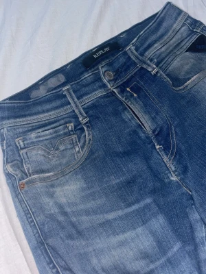 Replay anbass hyperflex - Säljer ett par blå jeans från Replay med snygg tvättad look och klassisk femficksmodell. Jeansen har normal midja och raka ben, tillverkade i mjukt denimtyg som ger en avslappnad känsla. Perfekta för dig som gillar stilrena och bekväma jeans.