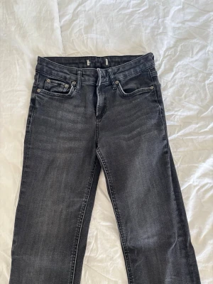Svarta bootcut jeans med slitningar - Säljer ett par svarta bootcut jeans med lätt slitna detaljer och klassisk femficksmodell. Jeansen har en snygg tvättad look och utsvängda ben. Perfekta för dig som gillar en avslappnad men trendig stil.