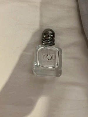 Stronger With You Intensely parfym - En elegant parfymflaska från Emporio Armani, Stronger With You Intensely. Flaskan är genomskinlig med rundade kanter och har en silverfärgad, metallisk kork. Modern och stilren design som passar perfekt i badrumshyllan.