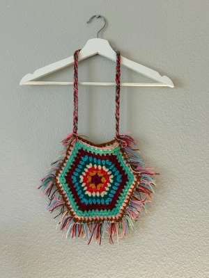 Vintage virkad handväska med fransar - Vintage handväska, virkad i flera färger som röd, turkos, brun, beige och rosa. Väskan har långa fransar runt kanterna och en flätad axelrem. I fint skick.