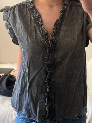 Grå volangblus med kort ärm - Assnygg blus med volanger. Köpt i USA. Jättefint skick, knappast använd! 