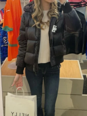 Svart pufferjacka från Armani - Snygg svart pufferjacka från Armani med en logga på armen. Jackan är som ny och är perfekt till höst och vinter! Sitter asbra och har även luva! Säljer pga att jag fick en ny i julklapp! Nypris 2000 kr!