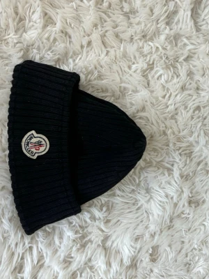 Svart ribbad mössa från Moncler - Säljer en svart ribbstickad mössa från Moncler one size