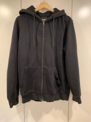 Svart zip hoddie - Säljer denna svarta zip up hoddie från Jack & Jones, hoddie har några få täcken på användning!