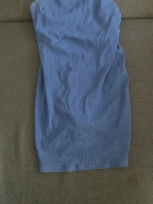 Blå ribbad ärmlös kortklänning - Säljer en blå ribbad kortklänning med smala axelband och kroppsnära passform. Klänningen är ärmlös och gjord i ett stretchigt material som känns mjukt mot huden. Enkel och stilren design som är lätt att matcha.