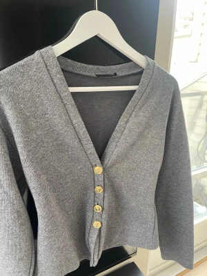 Grå kofta med guldfärgade knappar - Snygg grå kofta från ZARA i storlek M. Säljer för den inte kommit till användning 
