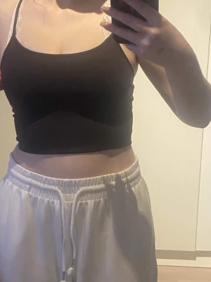 Mörkgrå träningsbh - En enkel och stilren mörkgrå bralette med smala justerbara axelband och mjuk, stretchig passform. Perfekt under linnen eller tröjor för en bekväm känsla. Inga synliga detaljer eller mönster, bara en clean look. Använd som linne förut. Tråden på banden har lossnat lite men deg är bara att klippa bort.