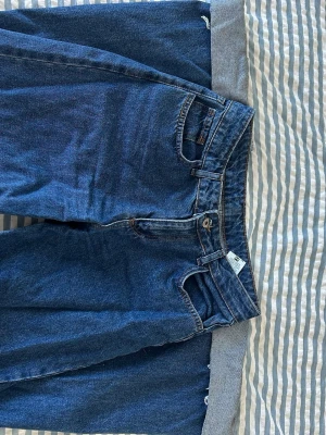 Blå raka jeans från Shein - Säljer ett par klassiska blå jeans från Shein med rak passform och hög midja. Jeansen har fem fickor, knappgylf och är gjorda i ett robust denimtyg. Perfekta för en avslappnad och stilren look.
