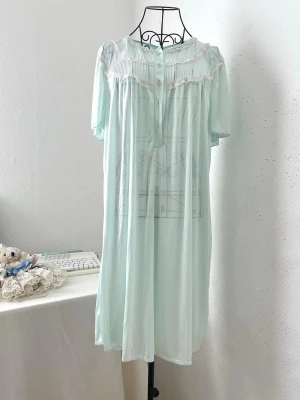 Ljusgrönt vintage nattlinne med spets - OBS! Defekt på baksidan (se sista bild). Sött ljusgrönt nattlinne i vintage-stil med korta ärmar, knappar framtill och plisserad överdel. Onesize fit all. Mannequins storlek: 34.