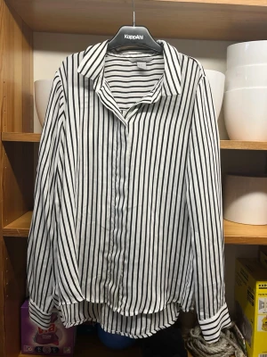 Randig skjorta från H&M - Säljer en vit skjorta med svarta vertikala ränder från H&M då den håller på att ligga runt hemma och används inte. Något biliggare vid snabba affärer!