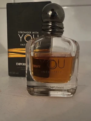 Emporio Armani Stronger With You Intensely - Emporio Armani Stronger With You Intensely är en parfym med varm bärnstensfärgad vätska i en elegant, genomskinlig glasflaska med rundade kanter och en metallisk, silverfärgad kork. Förpackningen är svart med guldiga detaljer och modern design. Vet ej hur många ml kvar men är lite mindre än på bilden priset är inte hugget i sten