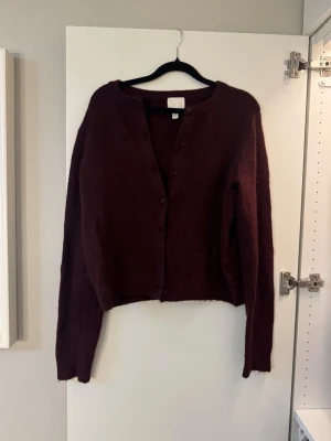 Vinröd kofta från H&M - Mysig vinröd kofta från H&M med knappar framtill. Koftan har långa ärmar och är tillverkad i ett mjukt stickat material som passar perfekt för kyliga dagar. Enkel och stilren design som är lätt att matcha med olika outfits.💕😃