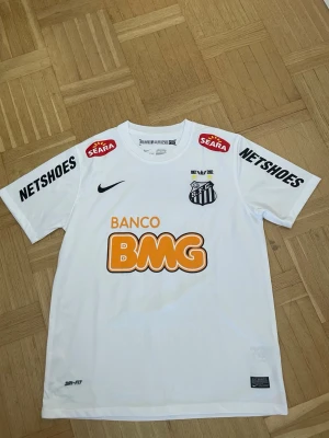 Vit Santos fotbollströja Neymar Jr - Säljer en vit Santos fotbollströja från Nike med Neymar Jr och nummer 11 på ryggen. Tröjan har flera sponsorloggor, rund hals och korta ärmar. Tillverkad i Dri-FIT material som andas, perfekt för träning eller match.