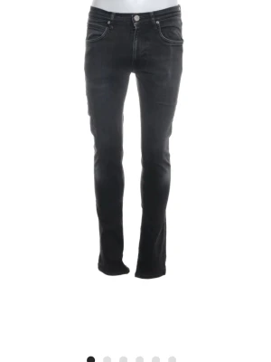 Mörk grå jeans - Snygga mörk grå jeans med smal passform och klassiska fem fickor. Jeansen har en lätt tvättad look och silverfärgade detaljer vid knappar och nitar. Perfekta för dig som gillar en stilren och modern vibe.