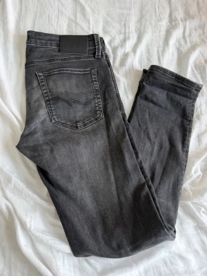 Jack & Jones  jeans - Snygga grå jeans i slim fit-modell med klassisk femficksdesign och svarta detaljer. Jeansen har en lätt tvättad look och raka ben. Perfekta till en avslappnad stil och passar till det mesta i garderoben.