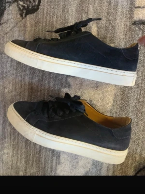 Mörkblå Boemos skor storlek 39 dam  - Stilrena mörkblå sneakers i mocka med vita sulor och mörkblå skosnören. Låg modell med klassisk design och diskreta sömmar. Insidan är ljusbrun vilket ger en snygg kontrast. Perfekta för dig som gillar enkel och clean stil.