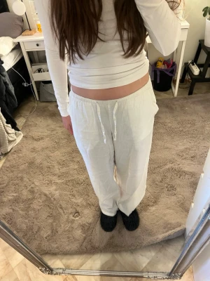 Vita linnebyxor - Säljer ett par vita linnebyxor med avslappnad passform och dragsko i midjan. Byxorna har raka ben och resår i midjan för extra komfort. Perfekta för en chill och stilren look. Materialet är luftigt linne som känns svalt och skönt. Storlek 152