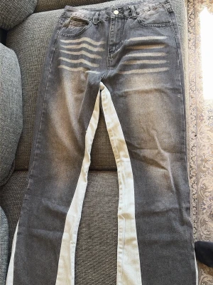 flared jeans - Unika grå jeans med kontrasterande vita paneler längs insidan av benen och råa, fransiga benslut. Jeansen har slitna detaljer framtill och en broderad detalj på ena bakfickan. Rak passform och cool streetstil.