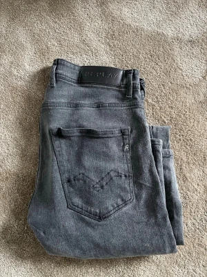 Mörkgrå Replay jeans med smal passform - Snygga mörkgrå jeans från Replay med smal passform och klassisk femficksdesign. Jeansen har en diskret tvättad look och detaljerad bakficka med broderi. Tillverkade i mjukt denimtyg som ger en bekväm känsla och stilren look.