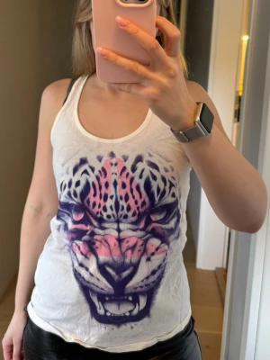 Vit sports topp med leopardtryck - Säljer ett vit sports topp med ett stort leopardtryck i lila och rosa på framsidan. 