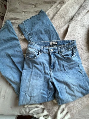 Ljusblå jeans från ONLY - Säljer ett par fina ljusblå jeans från ONLY med klassisk femficksmodell. Jeansen har snygga bakfickor med knappar! Superfint skick då de knappt hunnit bli använda! Storleken är S 32💛