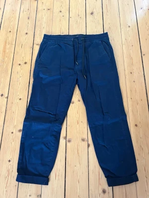 Mörkblå mjukisbyxor Hollister M - Mörkblå mjukisbyxor från Hollister med dragsko i midjan och resår. Byxorna har två sidofickor och uppvikta benslut. Sköna och avslappnade, perfekta för chill dagar. Materialet är mjukt och lätt, troligtvis bomullsblandning.