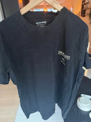 Svart t-shirt från Jack & Jones - Säljer en svart t-shirt från Jack & Jones Originals med tryck på bröstet där det står 'club del cortez, Baja California Sur'. Klassisk rund hals och korta ärmar. Perfekt till jeans eller shorts.