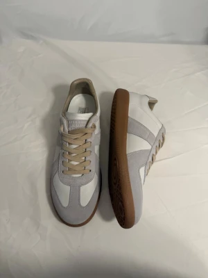 Maison margiela sneakers - Maison Margiela sneakers vit, mocka med beige detaljer och snörning. Klassisk rund tå och platt gummisula i brunt. Pris kan diskuteras Är du intresserad av fler bilder eller vill veta mer, är det bara att höra av dig!