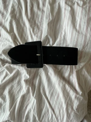 Svart bälte - Svart bälte från H&M. Passar någon med ganska smal midja då den är storlek xs. Funkar utmärkt till tex klänningar då det dessutom är för brett för att passa runt jeans. 