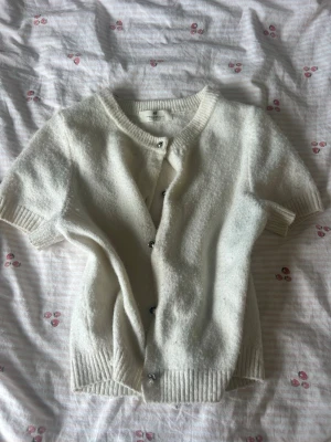 Cardigan  - Säljer denna super mysiga kortarmade koftan ifrån H&M! Perfekt nu till hösten men även en kylig sommarkväll. Koftan är Beige och i storlek 158-164. Passar barn men även tonåringar-är själv 15 och den är fortfarande perfek. Koftan har 5 silver knappar som är i full funktion, mjuk, bekväm, varm men även super snygg kofta som passar alla stilar, perfekt över ett linne!